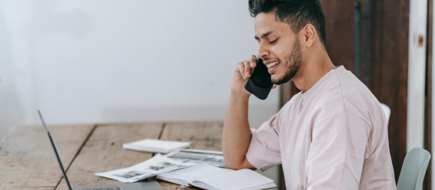 A man sat at a desk talking on a phone