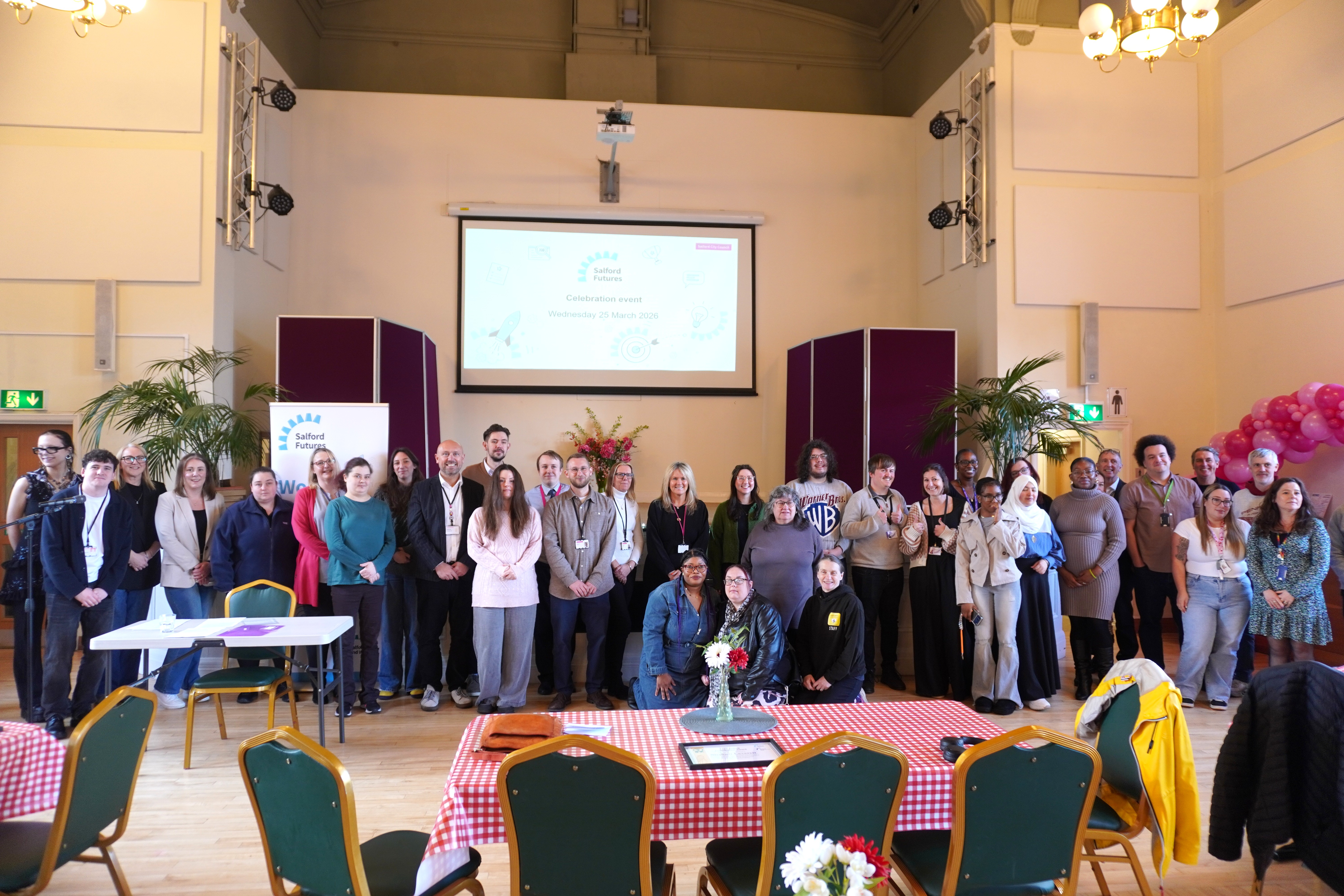 A group of people stood smiling in a town hall room