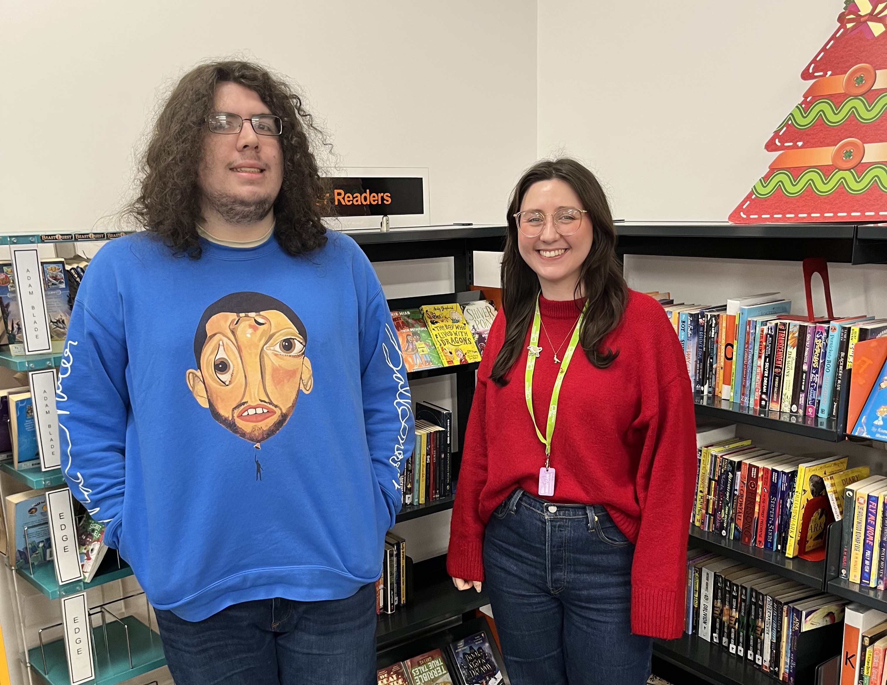 Two people stood in front of some bookshelves smiling